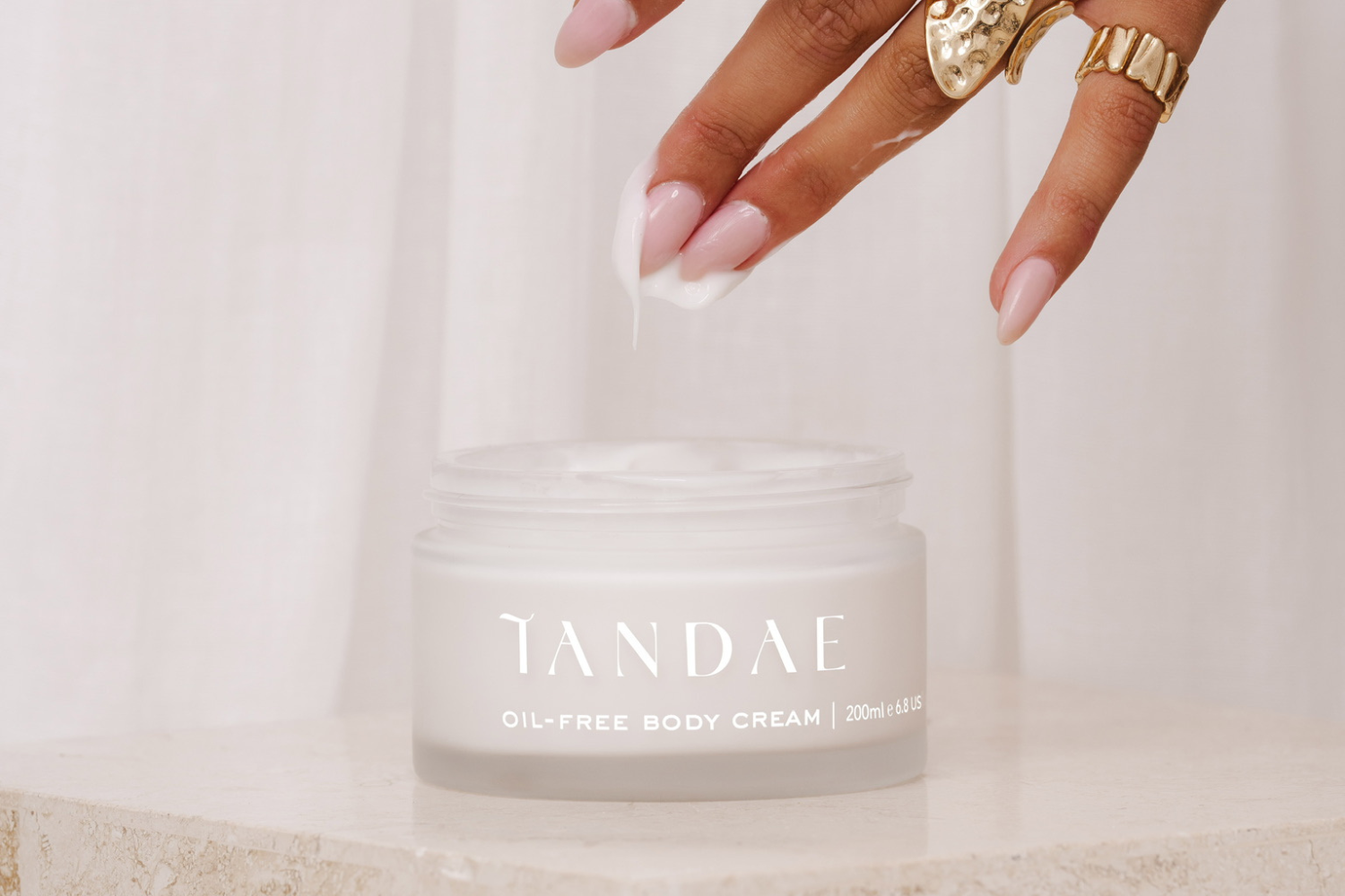 Image of the Tandae Oil-Free Body Cream and a hand that's just dipped into the formula